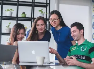Image of individuals around a laptop, emphasizing exchange.