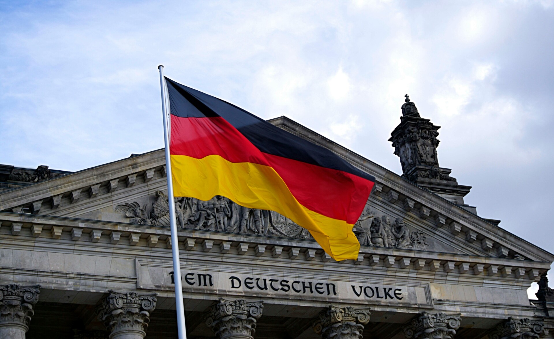 German flag waving in front of the Reichstag building in Berlin, with the inscription 